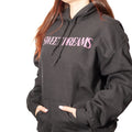 artist wearing a black hoodie with 'SWEET DREAMS' text in pink on a white background